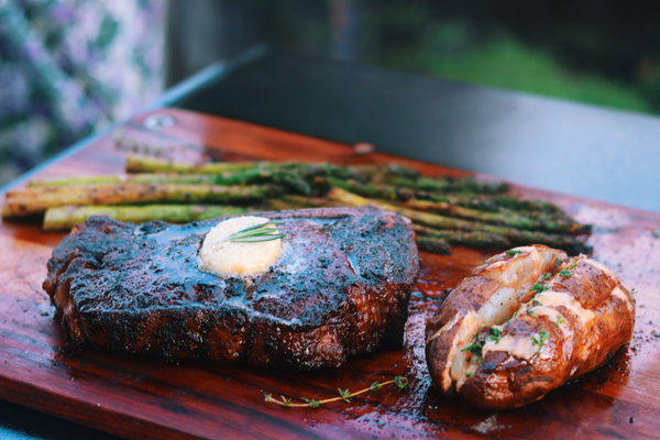 Reverse seared ribeye with a dark crust, topped with butter and rosemary