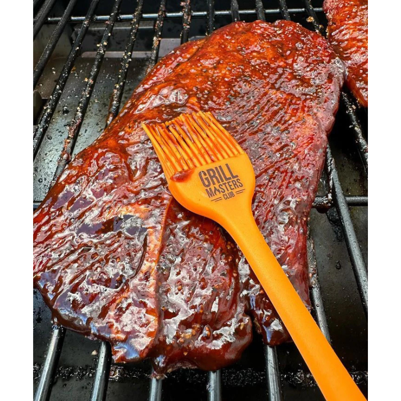 Pitmaster using BBQ mop brush to glaze ribs on a smoker