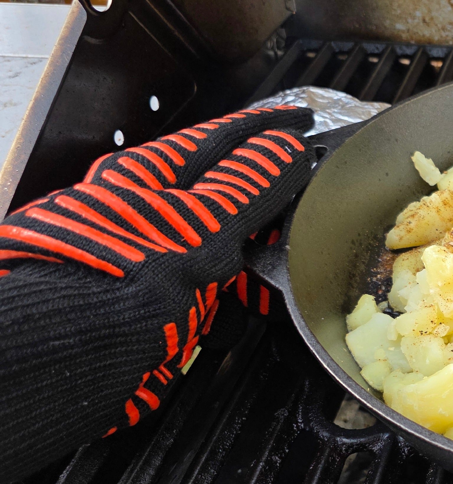 Closeup of Grilling Gloves Used to Grip a Hot Cast Iron Pan on a Grill