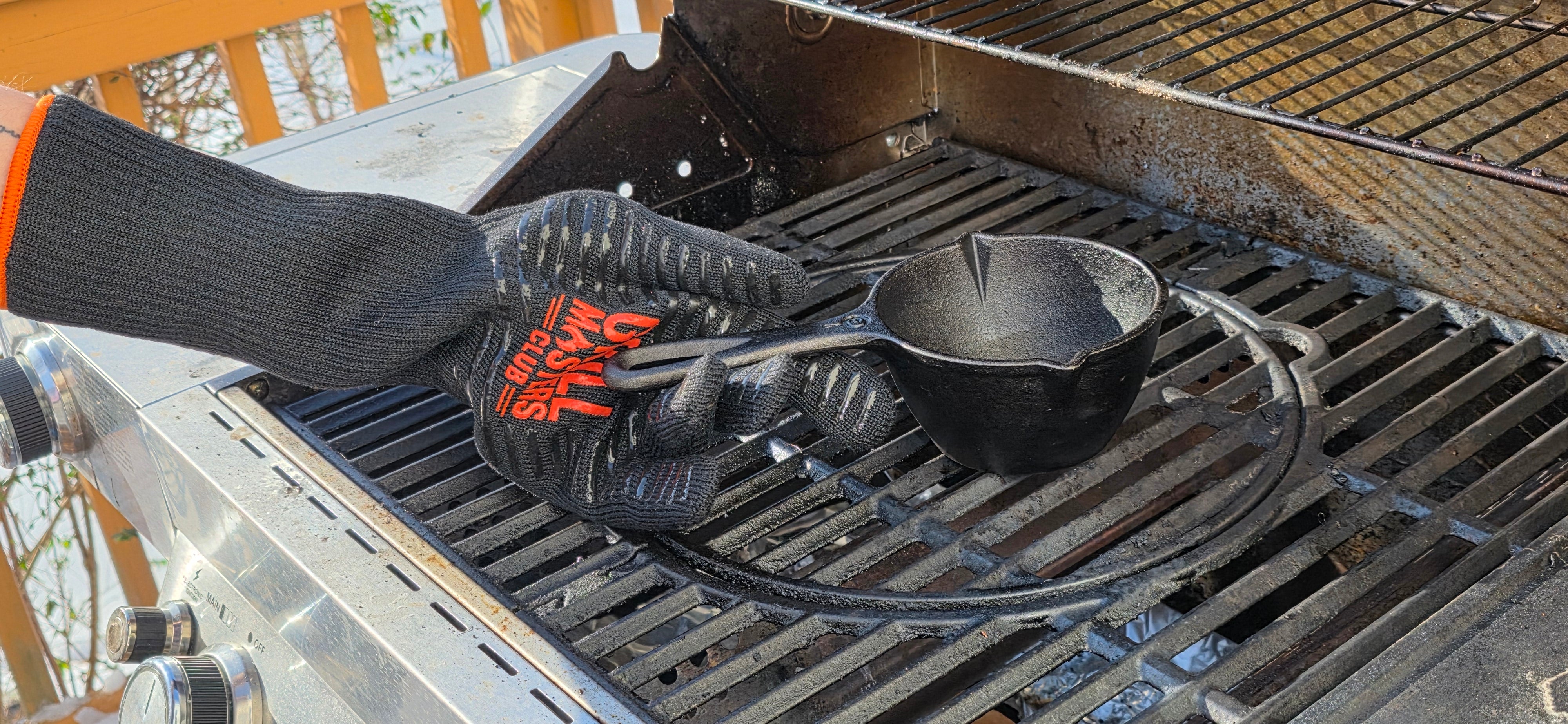 Pitmaster Wearing a Grilling Glove to Move a Cast Iron Pan on a Grill