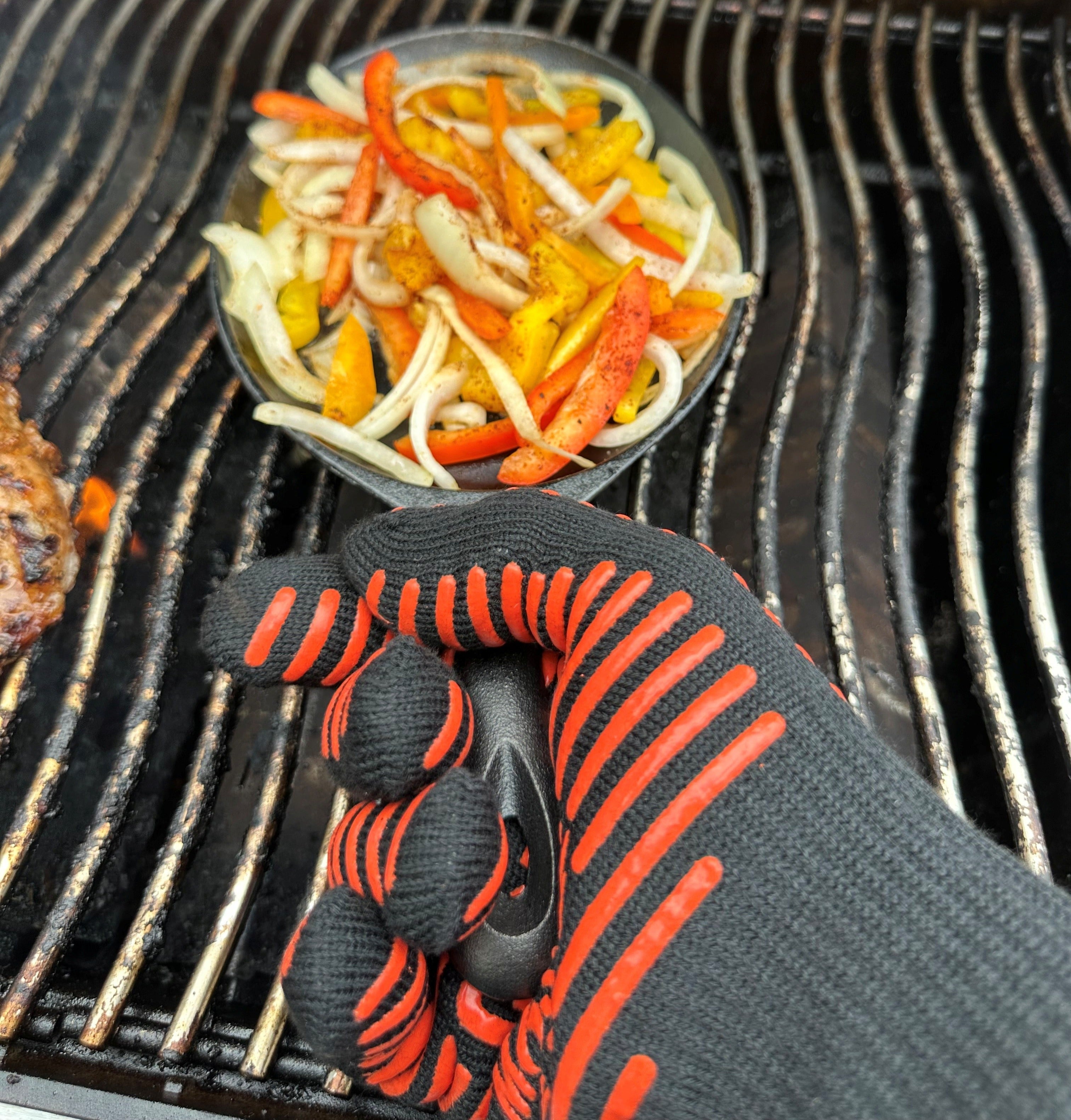 Closeup of Hand Wearing a Grilling Glove Holding a Hot Cast Iron Pan on a Grill