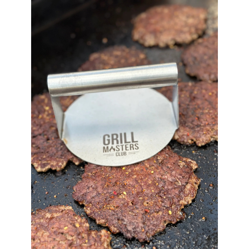 Stainless steel burger press flattening patty on grill for perfect smashburger